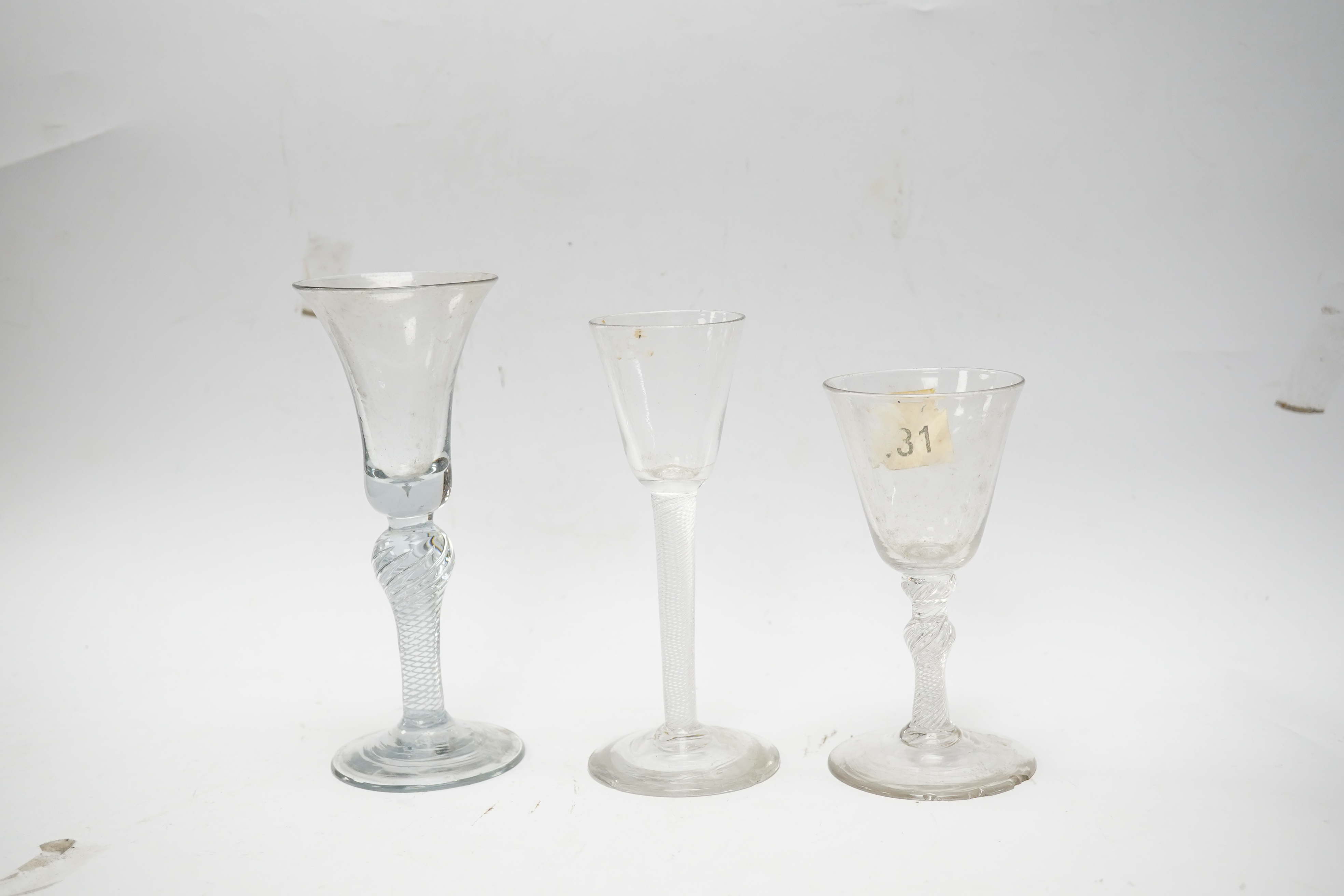 Three 18th century air twist stemmed wine glasses, tallest 16.5cm high. Condition - two having chips to edges of bases